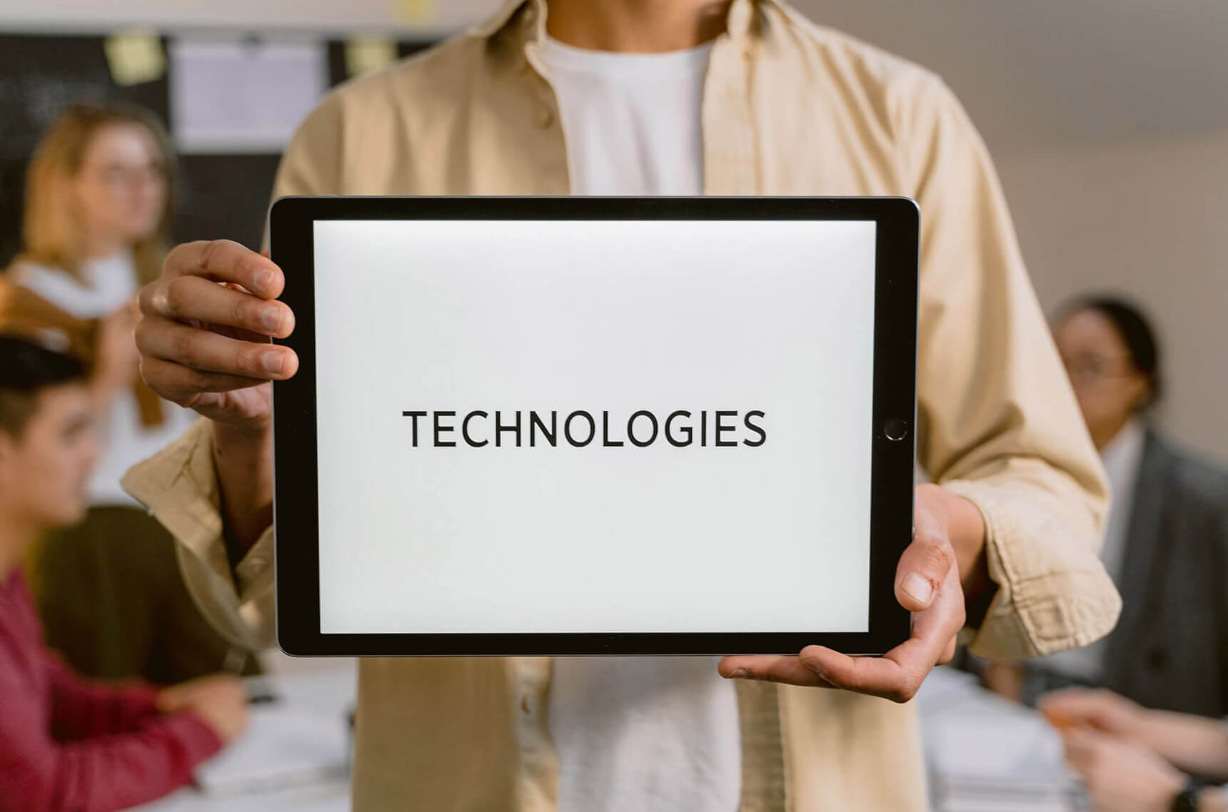 Person holding a tablet displaying the word technologies